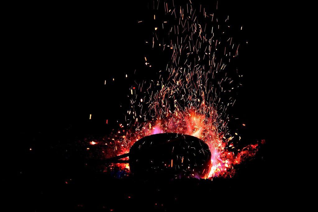 A dark image of molten metal projecting red sparks.